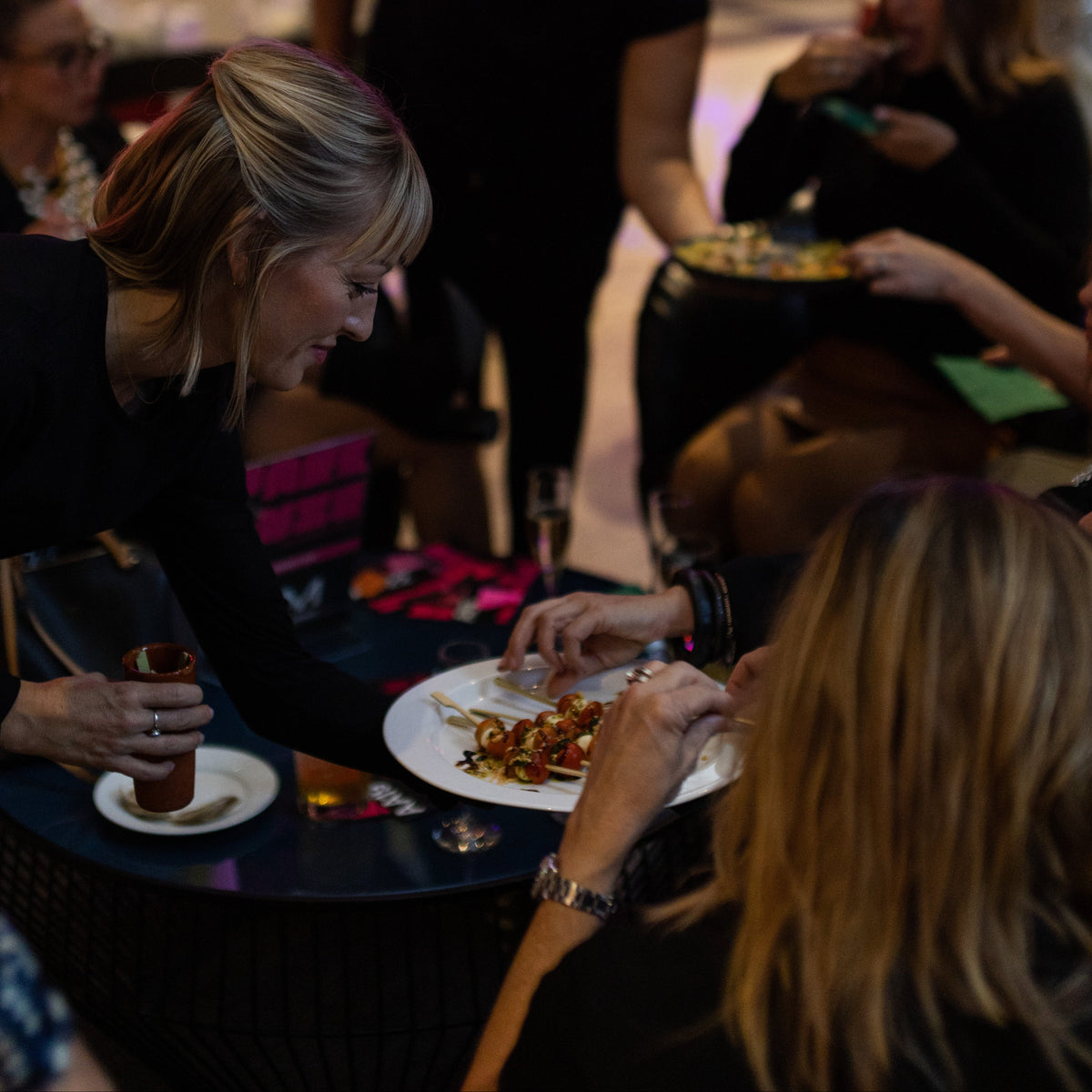 a server passing tomato and mozzarella skewers